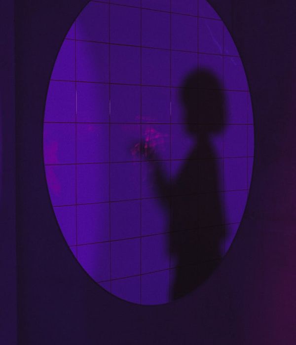 Woman in a calm yoga pose in a dark room with purple ambient light.
